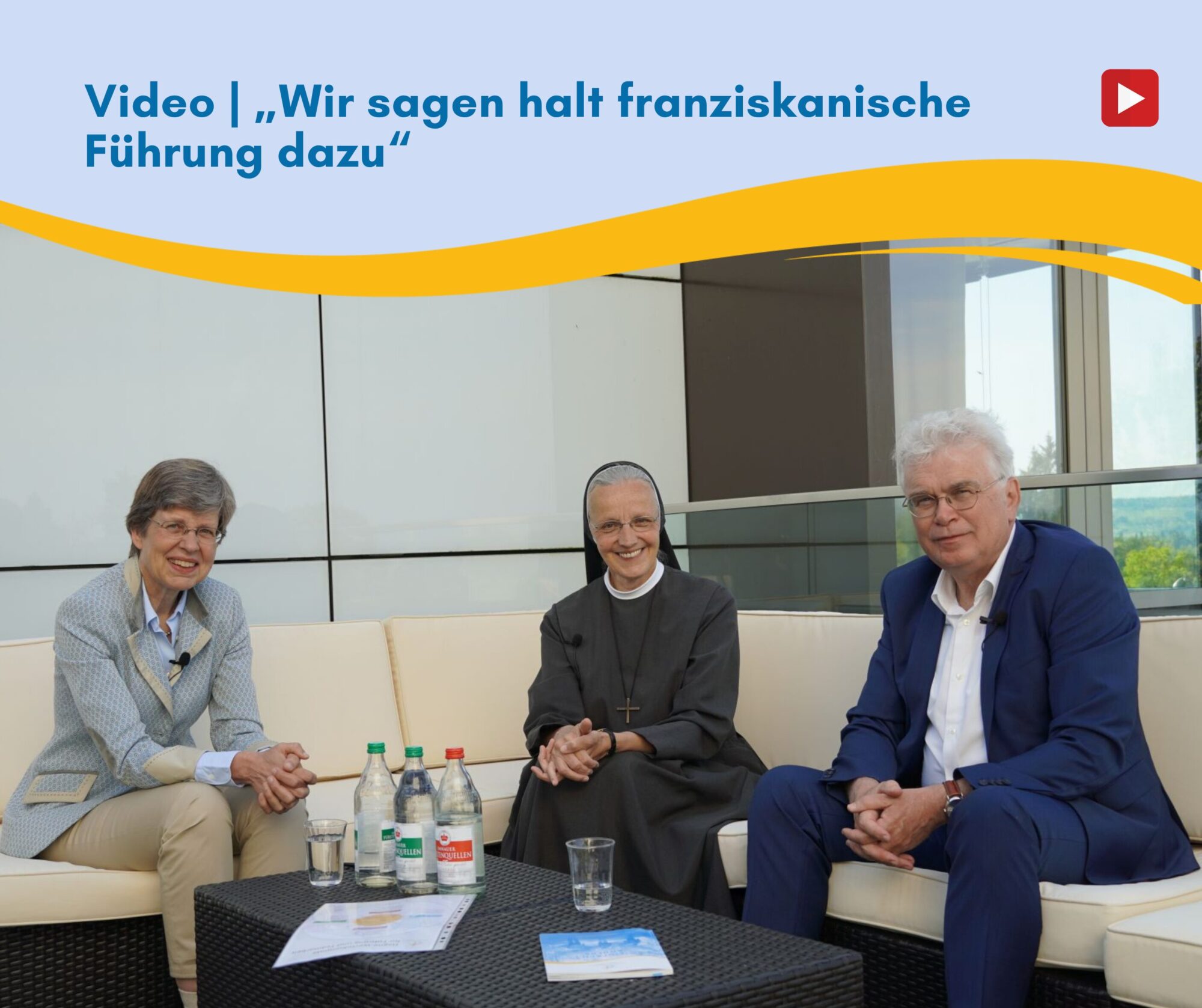 Zwei ältere Frauen und ein älterer Mann sitzen auf einem Sofa mit Getränken vor sich auf dem schwarzen Tisch