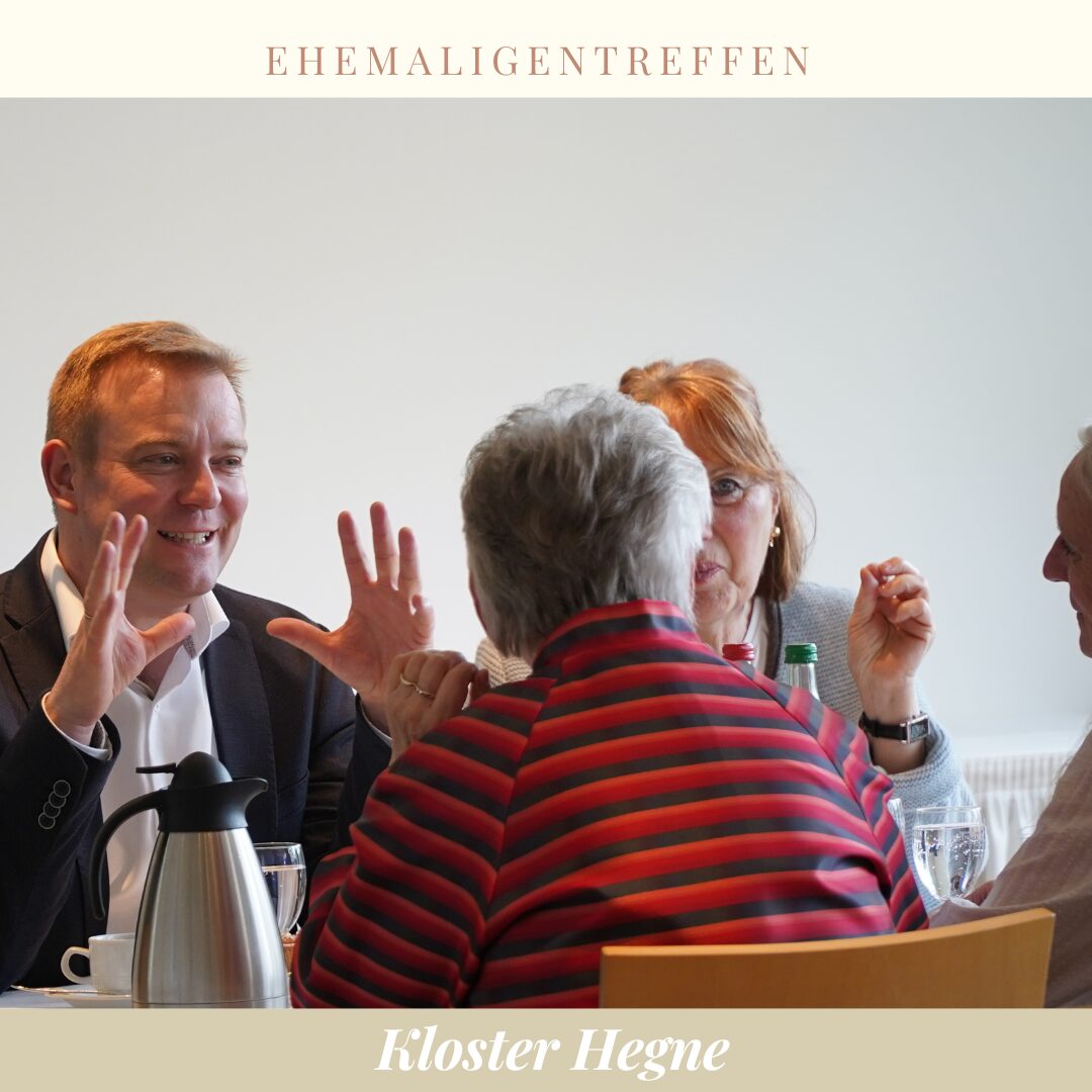 eine Person von hinten, die an einem Tisch mit Kaffee sitzt und sich mit zwei anderen ihr gegenübersitzenden Personen unterhält