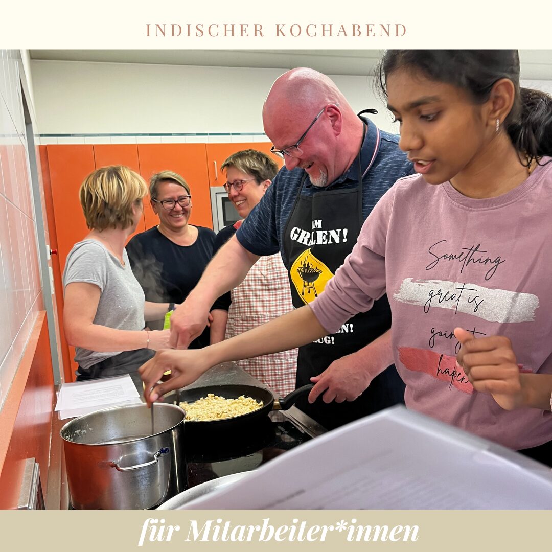 zwei Personen beim Koche am Herd im Hintergrund stehen Menschen, die sich unterhalten