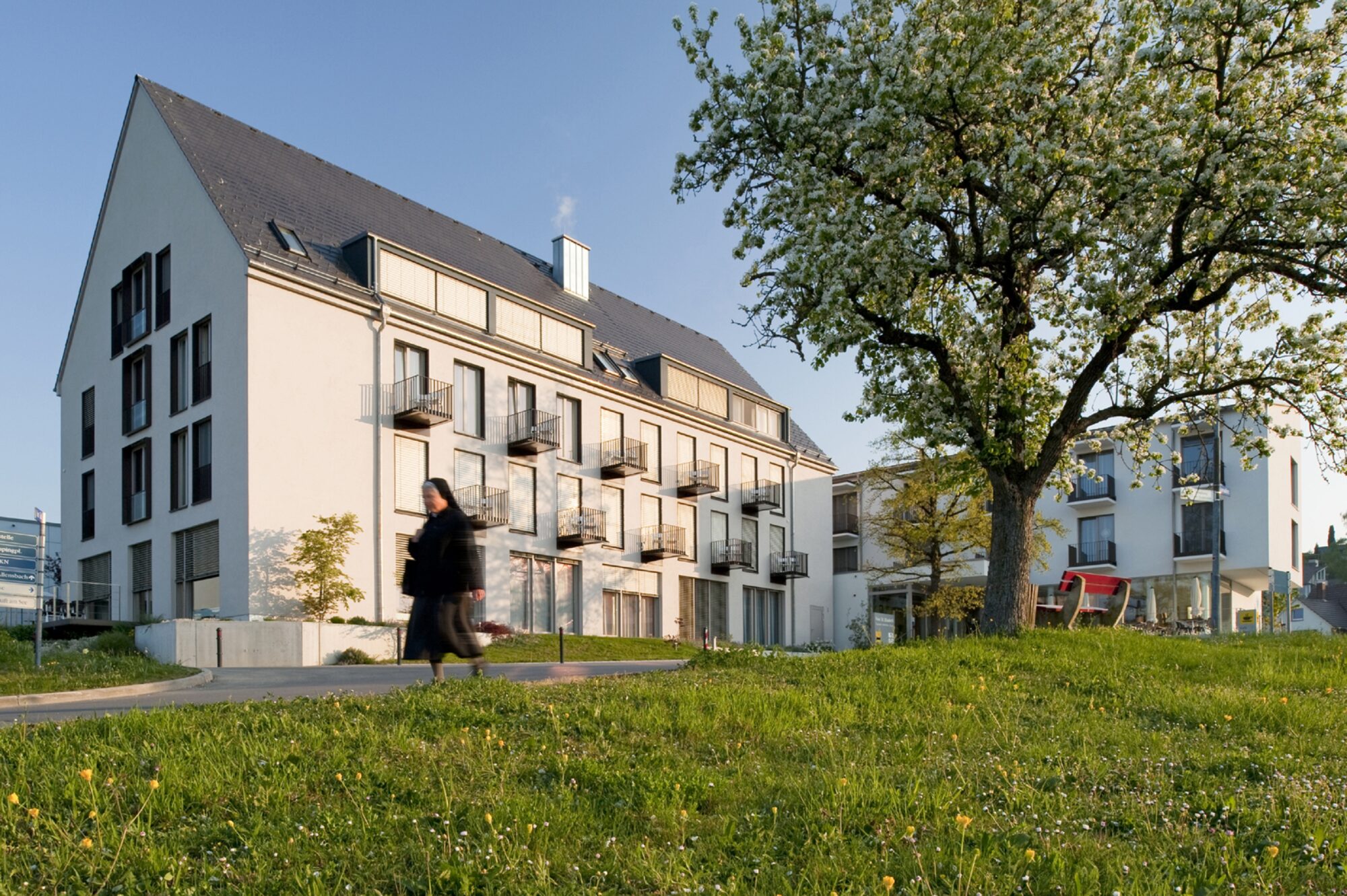 Eine Nonne läuft im Frühling vor einem Wohnhaus